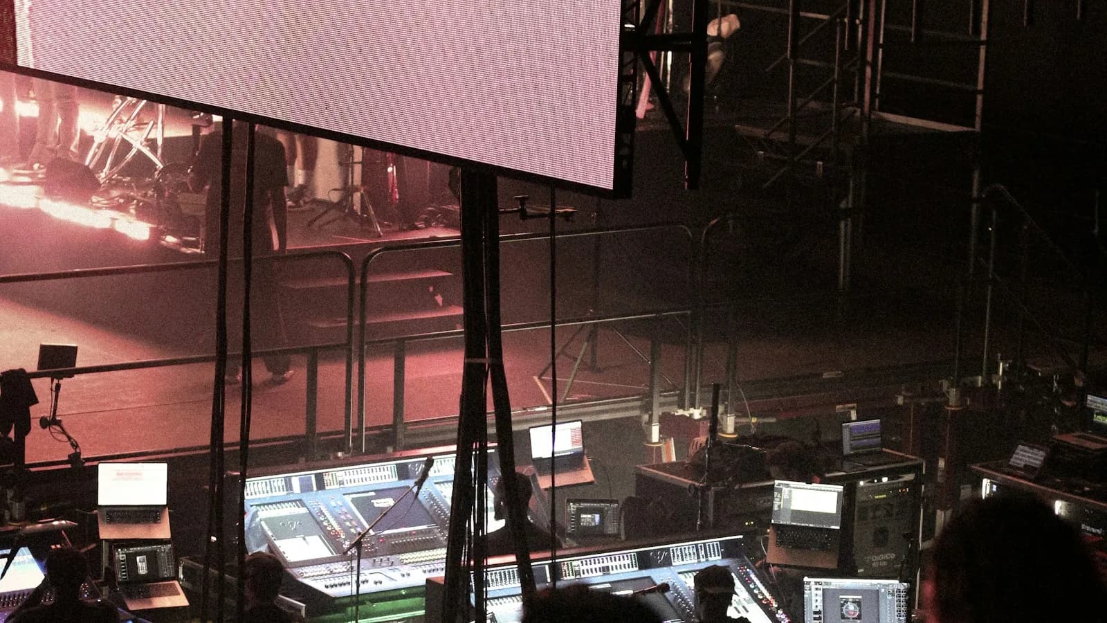 En régie, une équipe de production et de coordination travaille devant les écrans de contrôle et de mixage pendant un concert.